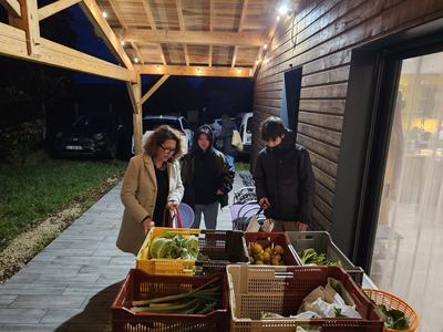 Adhérents choisissant leurs légumes bio dans les cagettes, le soir